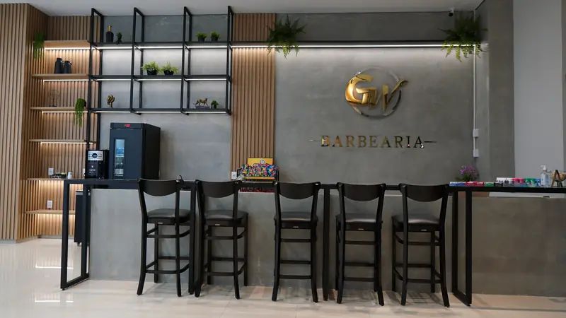 Bar da GW Barbearia com banquetas e logo na parede